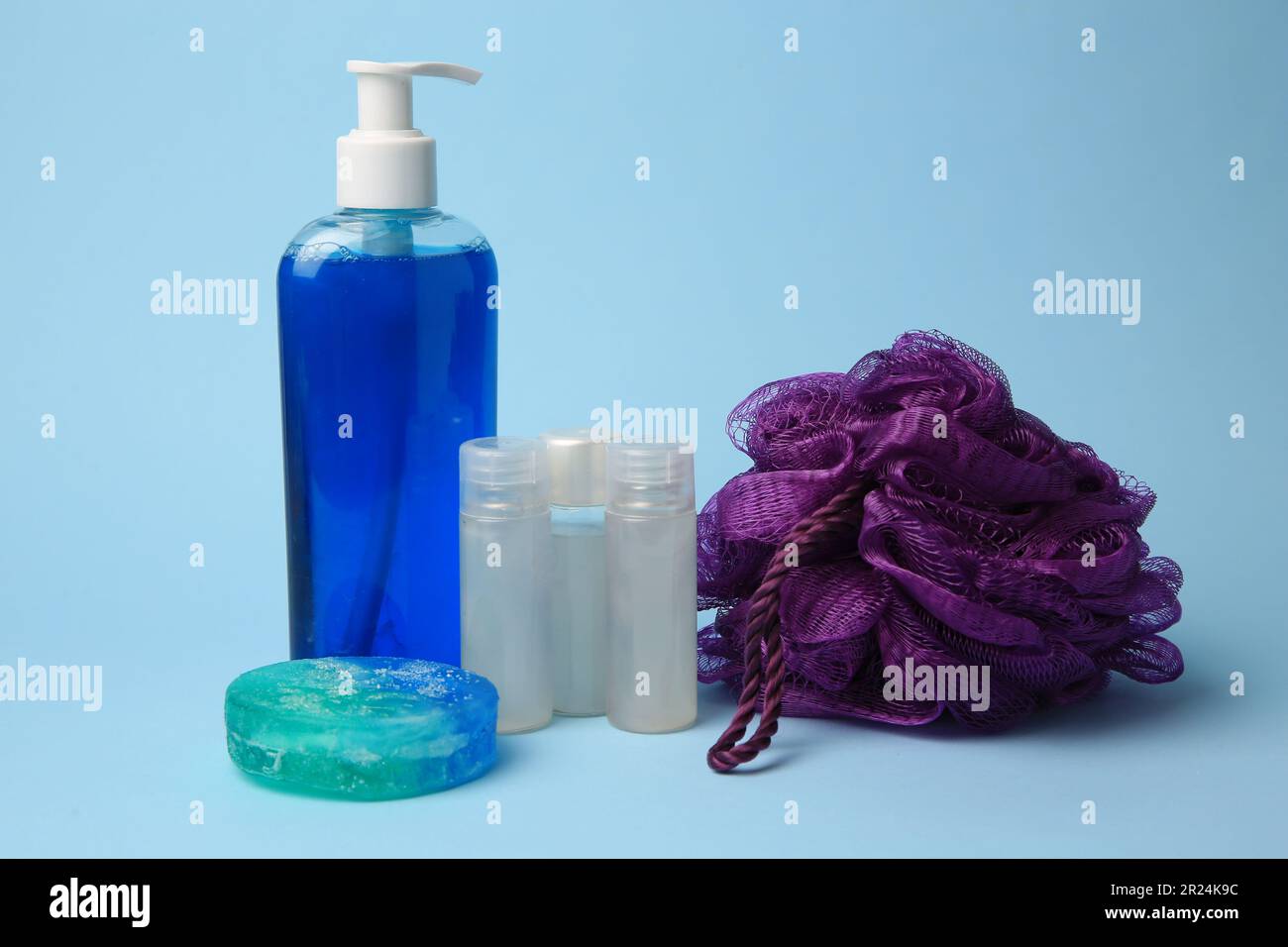 Souffleur de douche violet et produits cosmétiques sur fond bleu clair Banque D'Images