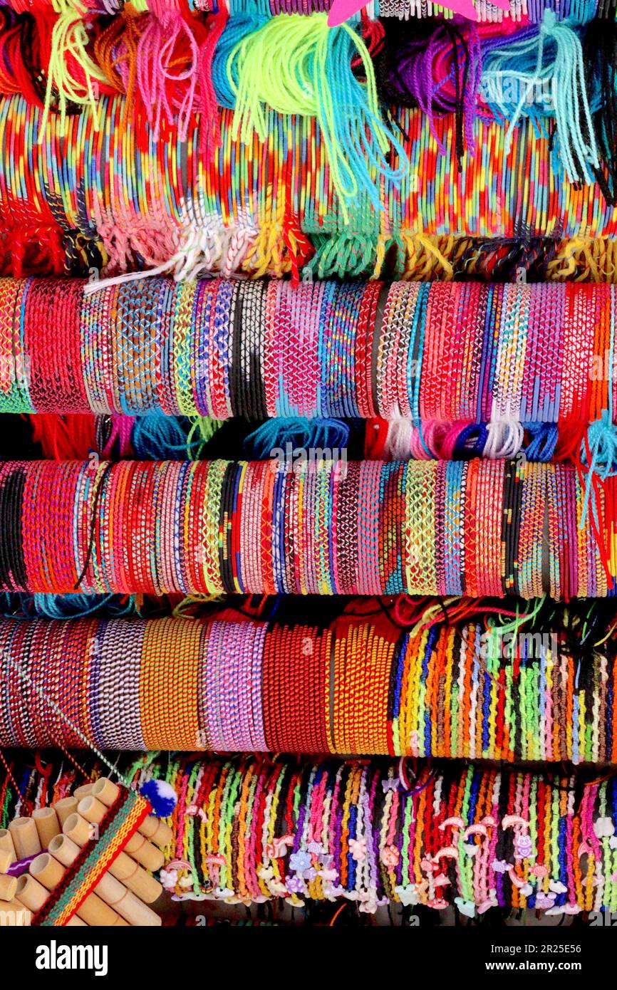 Bracelets colorés présentés avec des vêtements tendance offerts en vente sur un marché stalle ajacent à la marina à Alicante, Espagne, avril 2023. Banque D'Images