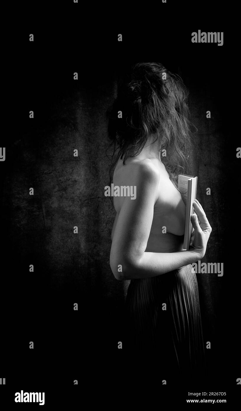 Femme en jupe noire lisant un livre en attitude romantique III Banque D'Images
