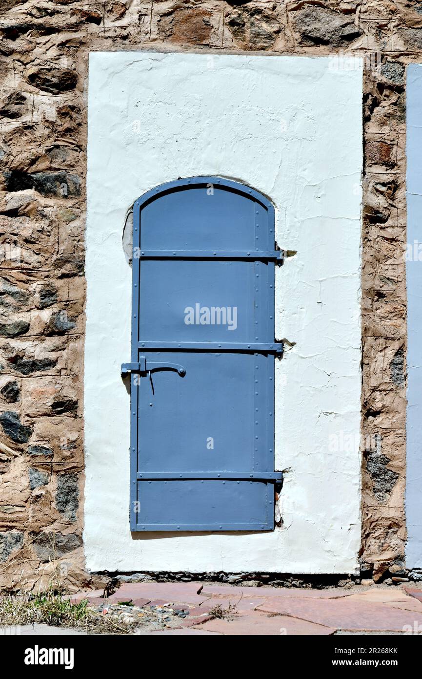 Porte de bâtiment abstraite avec pierre multicolore et coulis clair avec porte grise ou grise sur fond de ciment ou de stuc. Banque D'Images