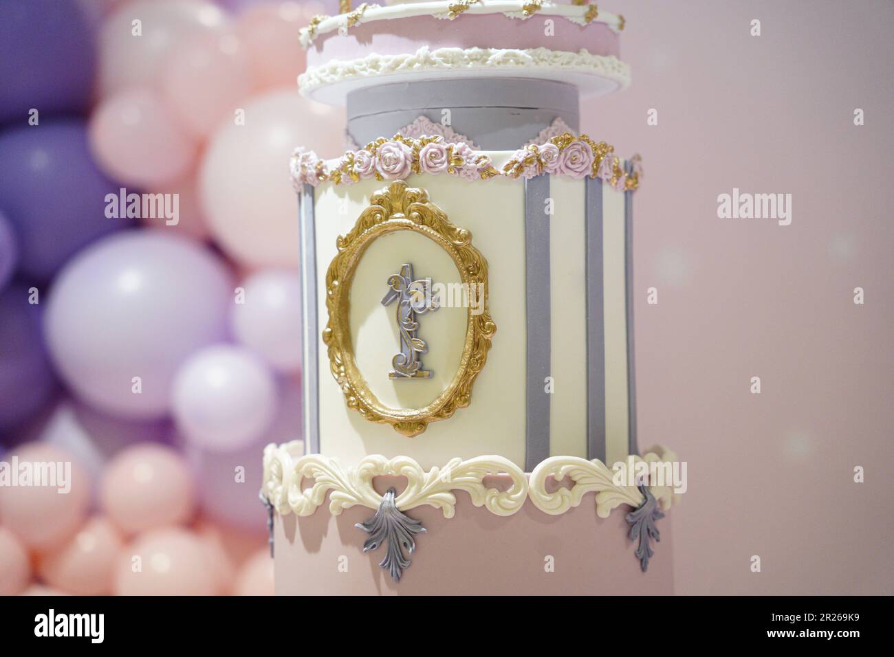 Gâteau de princesse d'anniversaire pour enfant 1st, gâteau rose et violet pour le premier anniversaire gros plan et isolé sur un fond rose avec des ballons. Banque D'Images