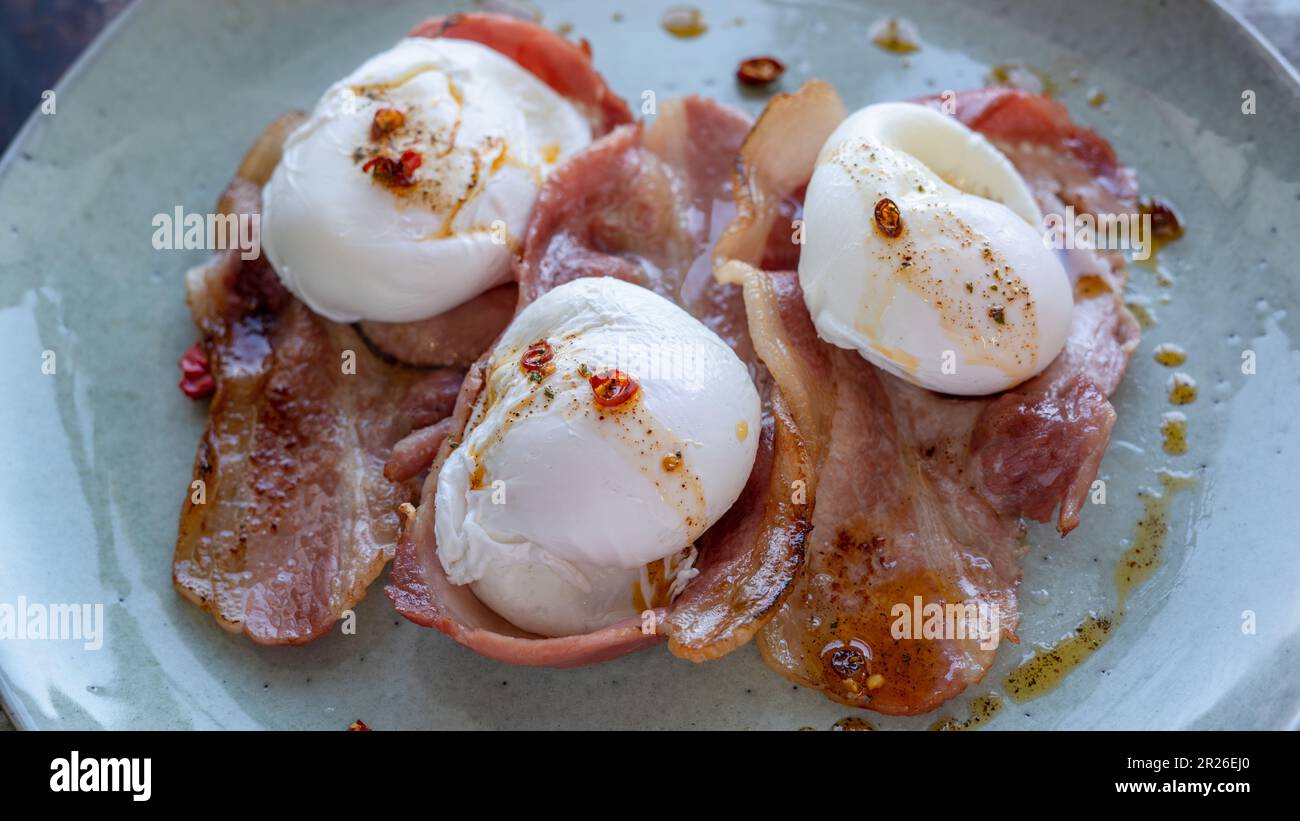 L'arbre écrase le bacon avec des œufs pochés et de la sauce Chili sur une assiette avec une vue latérale rustique. Banque D'Images