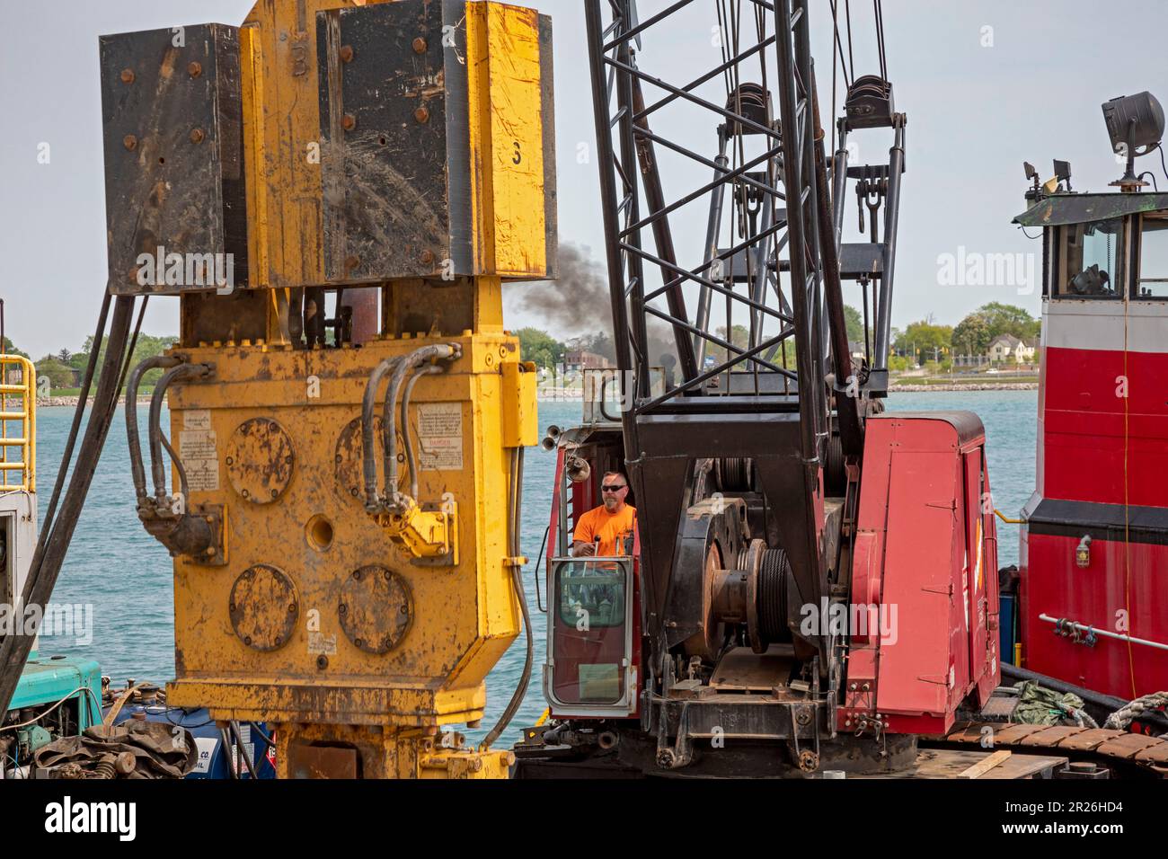 Detroit, Michigan - les travailleurs réparent le sentier côtier le long de la promenade côtière de Detroit à l'aide d'un conducteur de pieux monté sur une barge sur la rivière Detroit. Banque D'Images