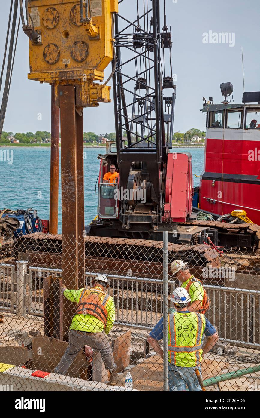 Detroit, Michigan - les travailleurs réparent le sentier côtier le long de la promenade côtière de Detroit à l'aide d'un conducteur de pieux monté sur une barge sur la rivière Detroit. Banque D'Images