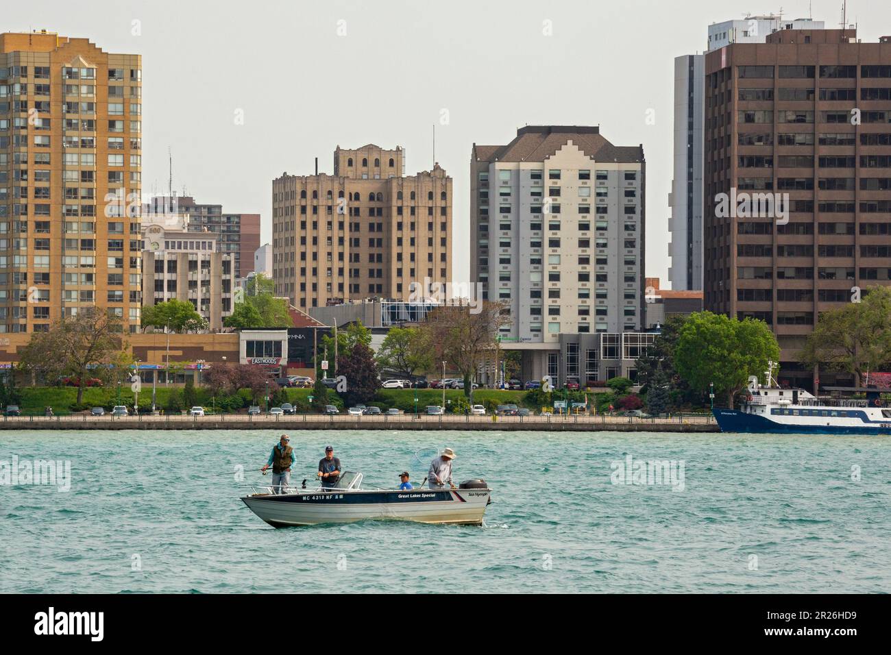 Detroit, Michigan - quatre hommes pêchant à partir d'un petit bateau sur la rivière Detroit, qui forme la frontière entre les États-Unis et le Canada. Au fond Banque D'Images