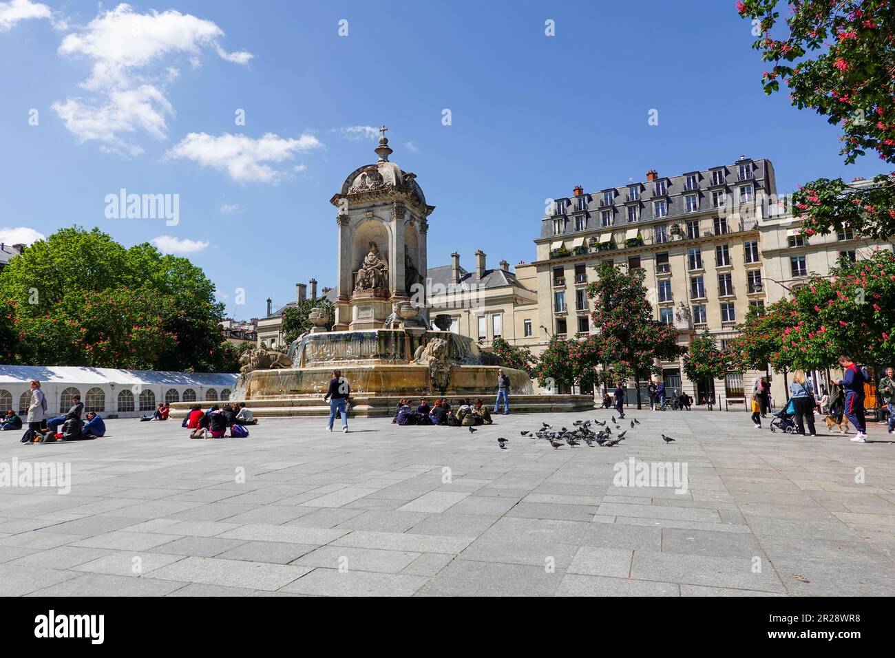 Personnes assises autour de la fontaine à la place Saint-Sulpice dans le 6th arrondissement, par une journée ensoleillée à Paris, France. Banque D'Images