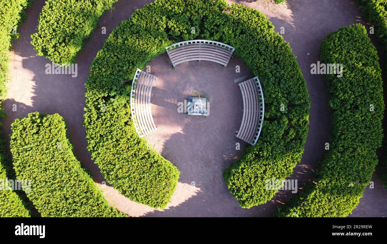 Une vue aérienne des buissons concentriques qui sont divisés autour d'un groupe de trois bancs. Banque D'Images