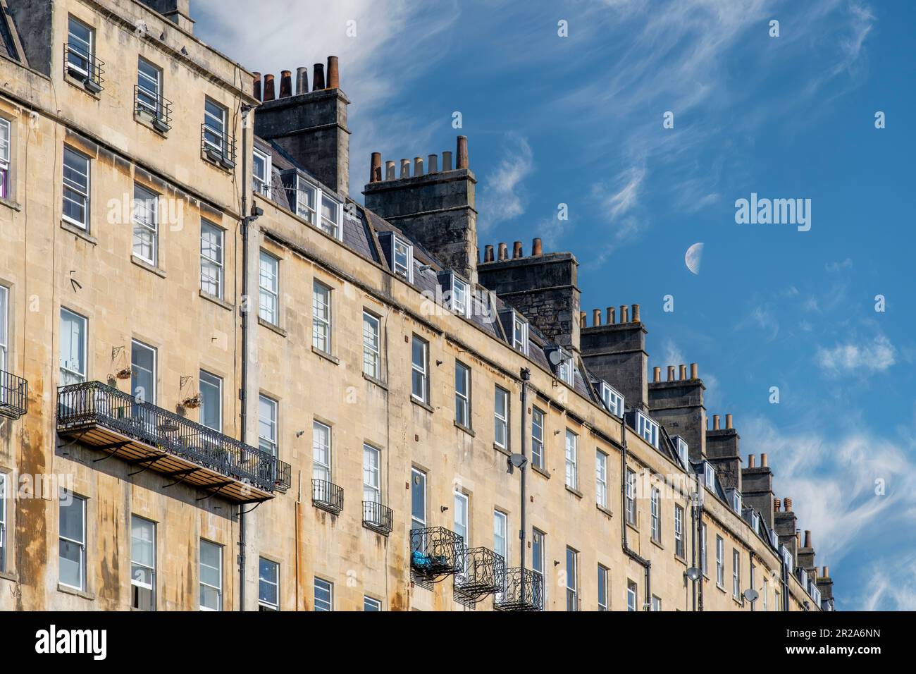 Vue à angle bas d'une longue rangée de maisons de ville géorgiennes avec toits et cheminées caractéristiques à Bath, Sommerset, Royaume-Uni contre un ciel bleu avec exploit Banque D'Images
