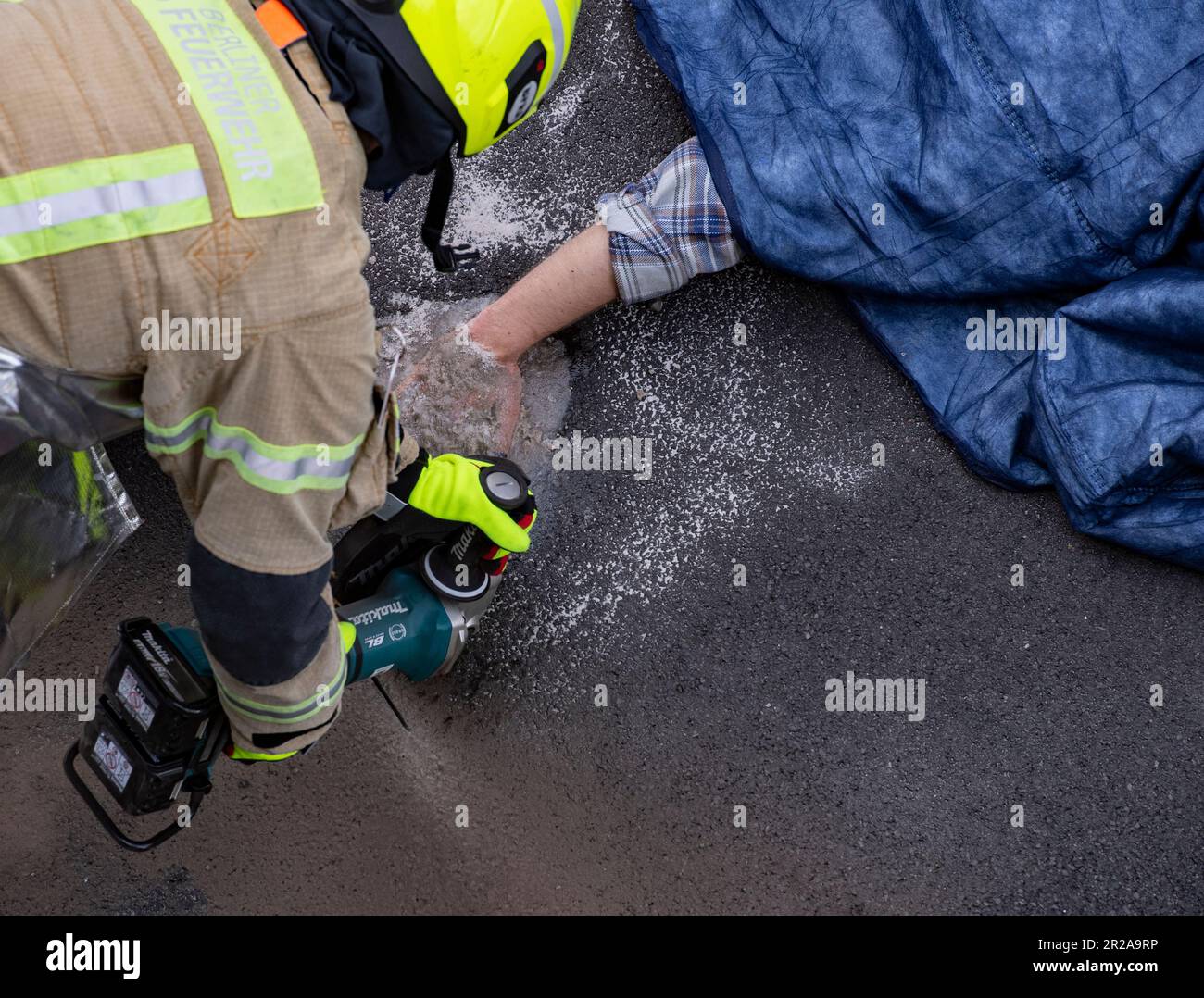 Berlin, Allemagne. 18th mai 2023. Un pompier travaille pour déloger de l'asphalte un activiste du groupe Letzte Generation qui s'est coincé à la chaussée sur l'autoroute A100 près de la sortie Kurfürstendamm. Plusieurs écologistes ont de nouveau bloqué l'autoroute de la ville. Credit: Paul Zinken/dpa/Alay Live News Banque D'Images