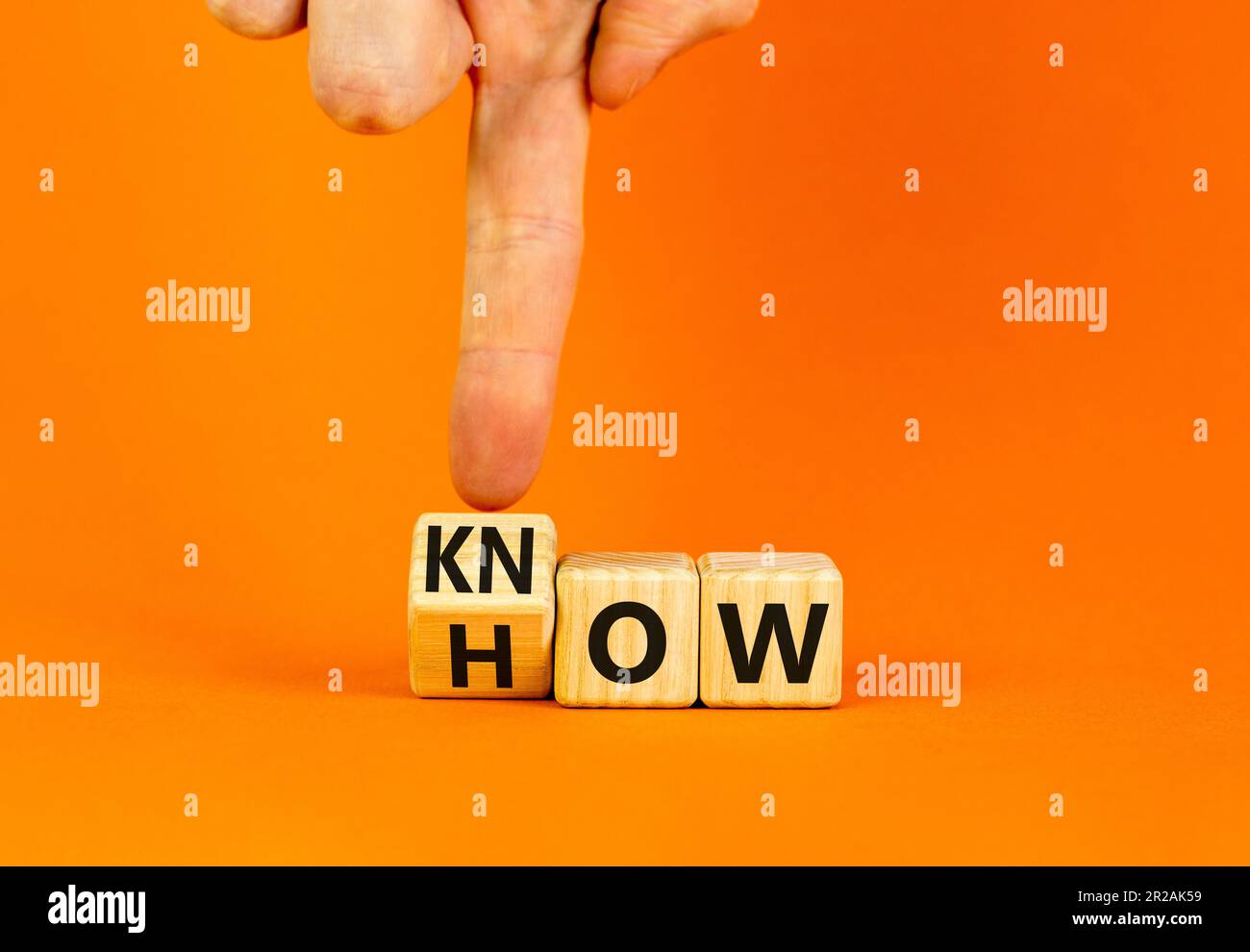 Symbole savoir-faire. L'homme d'affaires tourne des cubes en bois et change le mot Comment savoir. Belle table orange fond orange. Copier l'espace. Affaires et k Banque D'Images