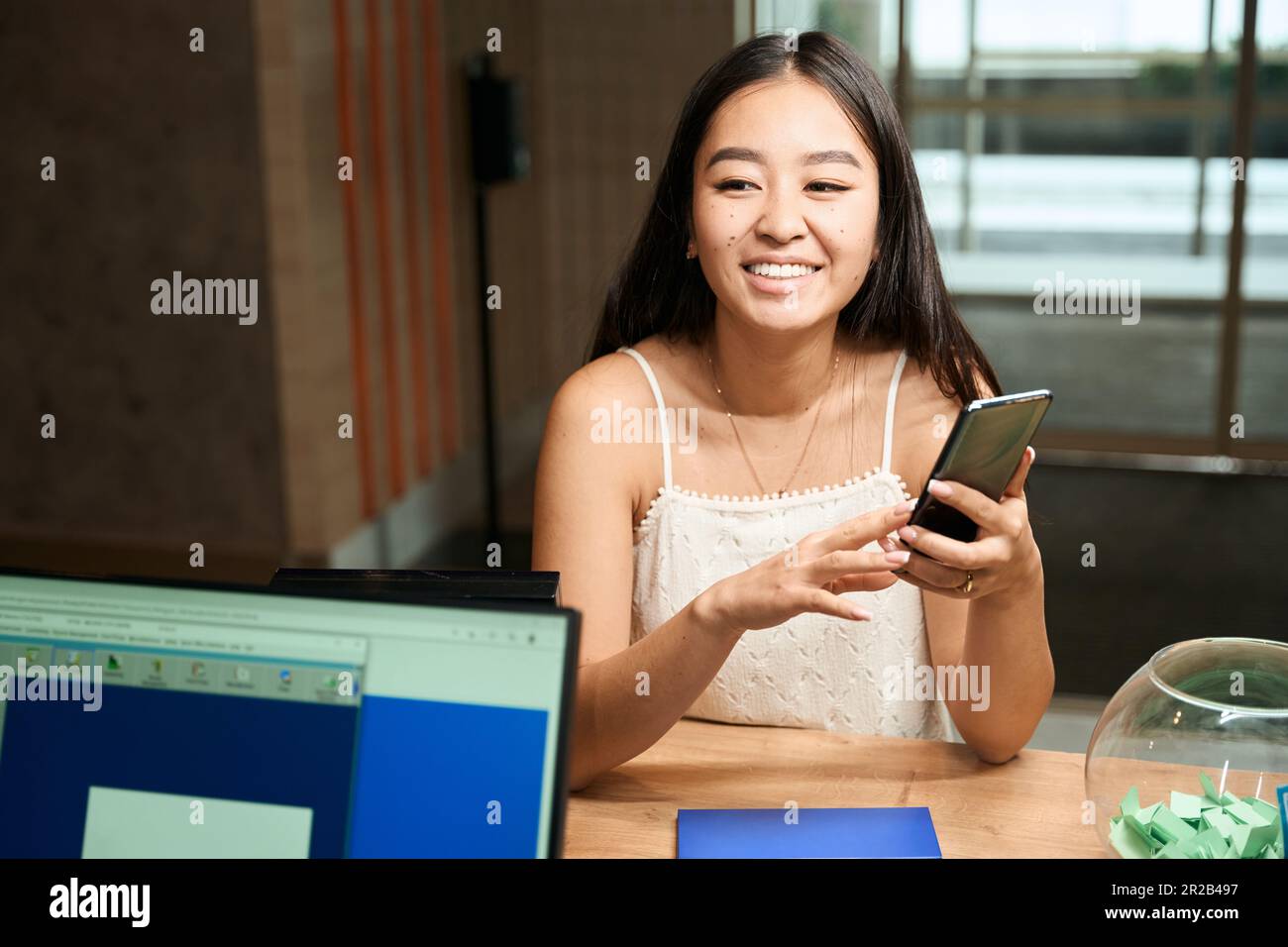 La femme asiatique s'amuse avec un smartphone entre ses mains Banque D'Images