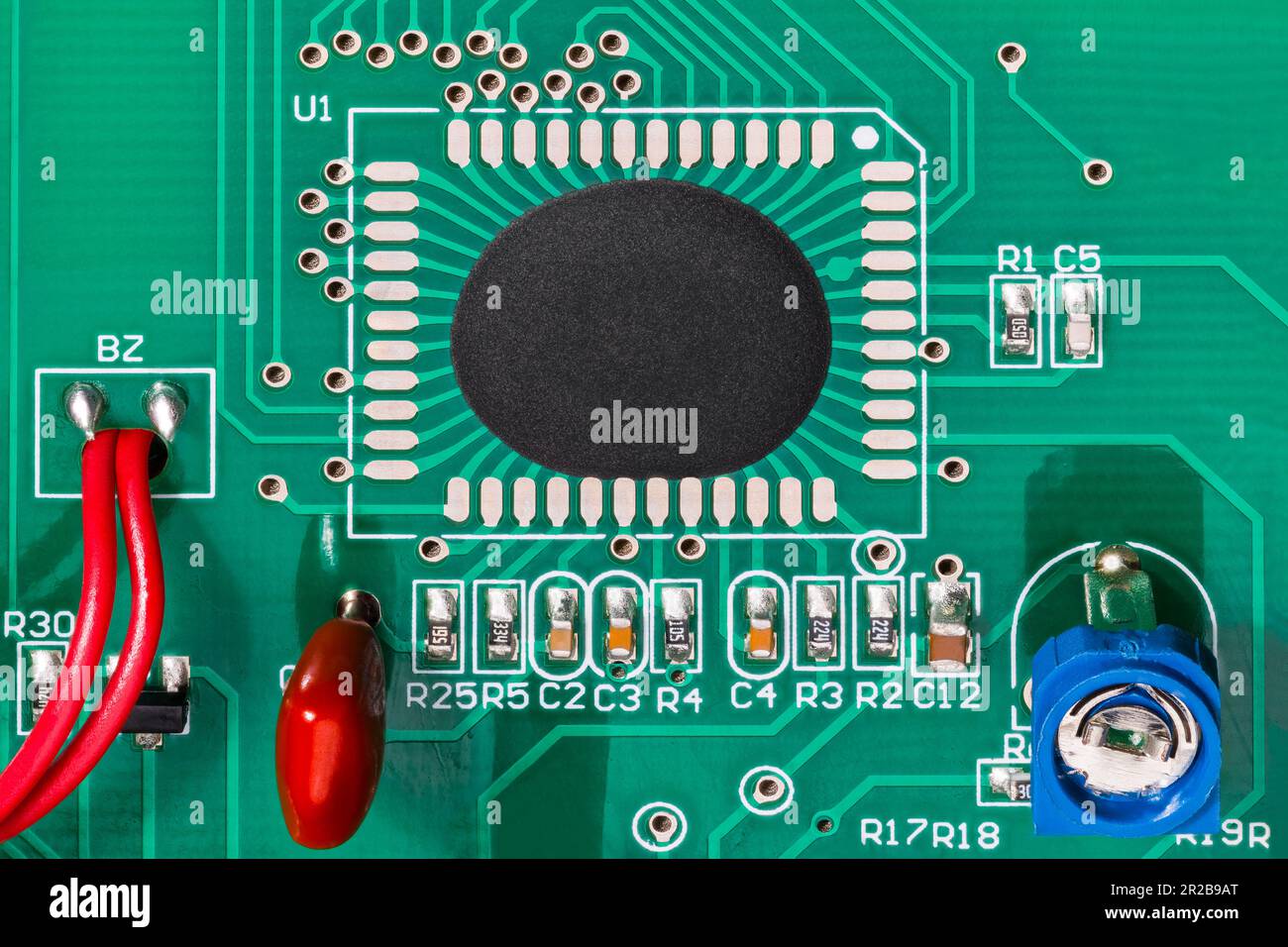Assemblage de circuit intégré sur circuit imprimé à texture verte avec fils rouges. Microchip dans les composants électroniques et les points de chute époxy. Potentiomètre. Banque D'Images