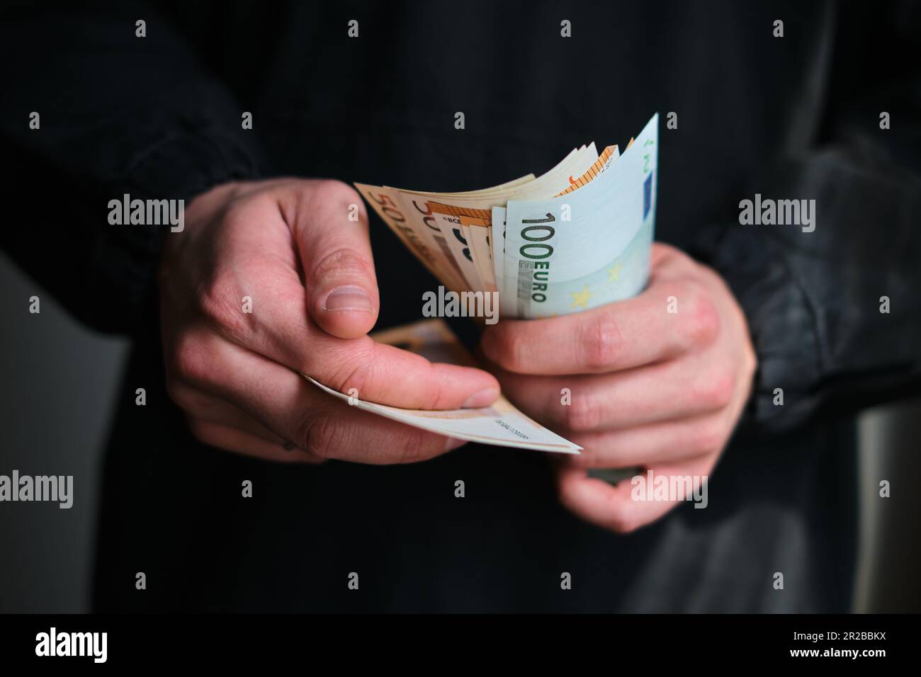 L'homme tient de l'argent entre ses mains. Espèces en euros pour paiement ou échange. Les hommes comptent le salaire en billets en euros. Économiser de l'argent, retrait dépôt bancaire Banque D'Images