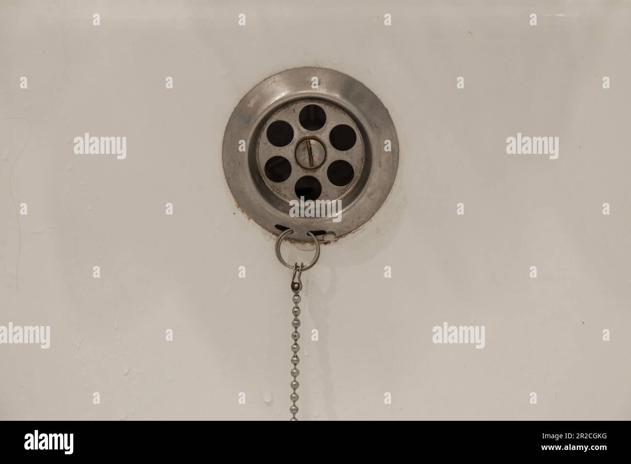 Eau de drainage avec bouchon en caoutchouc de drainage sur la baignoire de douche blanche de près Banque D'Images