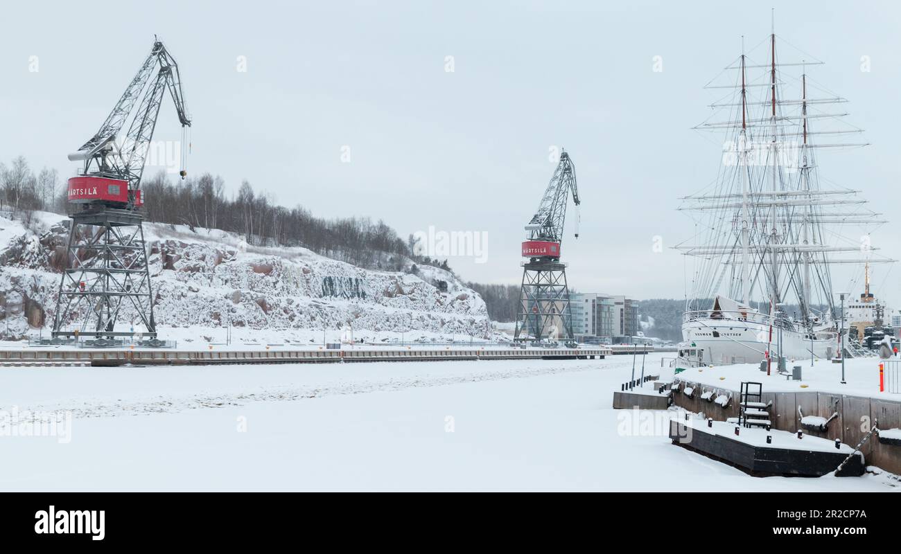 Turku, Finlande - 17 janvier 2016: Vue sur le port de Turku avec des grues portales et des bateaux à voile amarrés sur la côte de la rivière aura par une journée d'hiver Banque D'Images