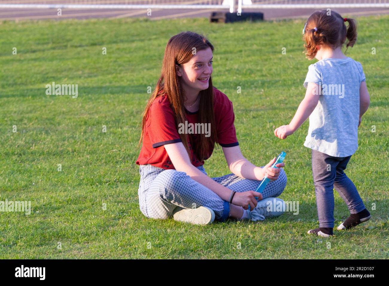 Une adolescente joue avec une petite fille à un festival de musique rural du Suffolk Banque D'Images