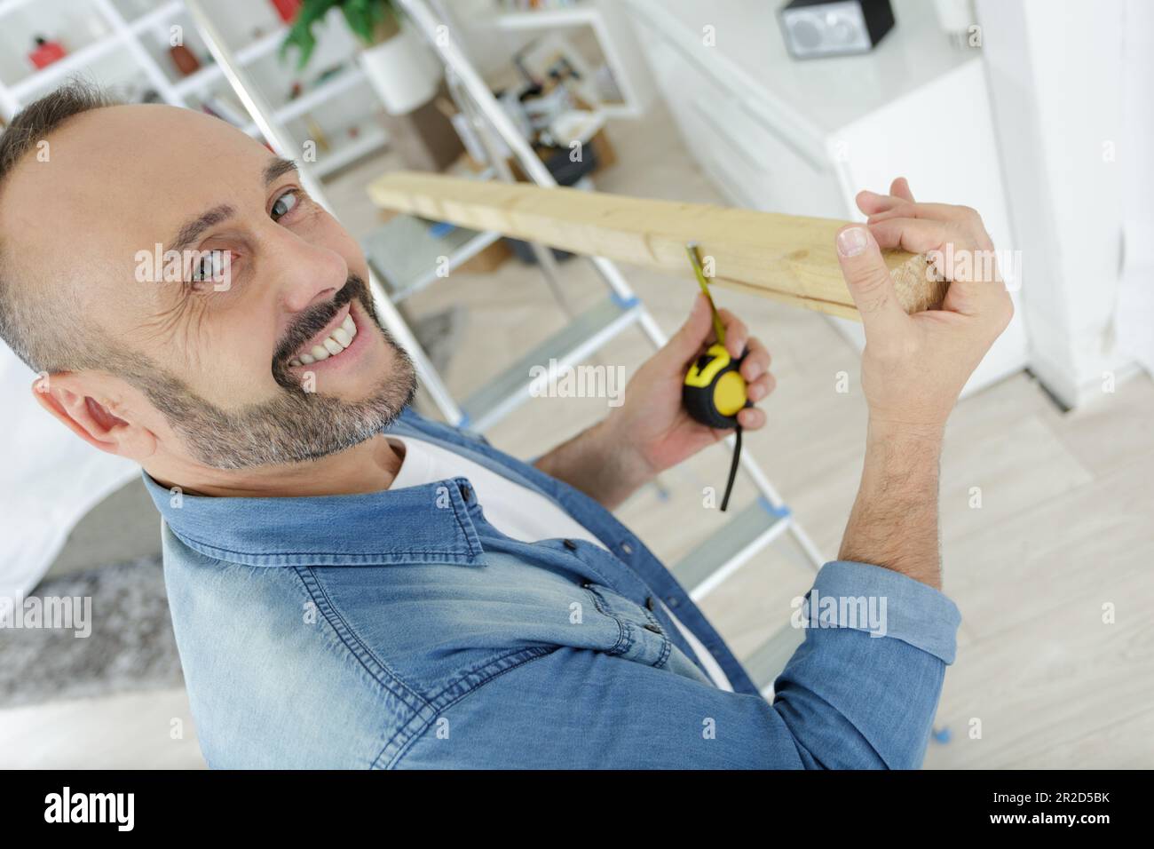 l'homme rit tout en mesurant le bois à la maison Banque D'Images