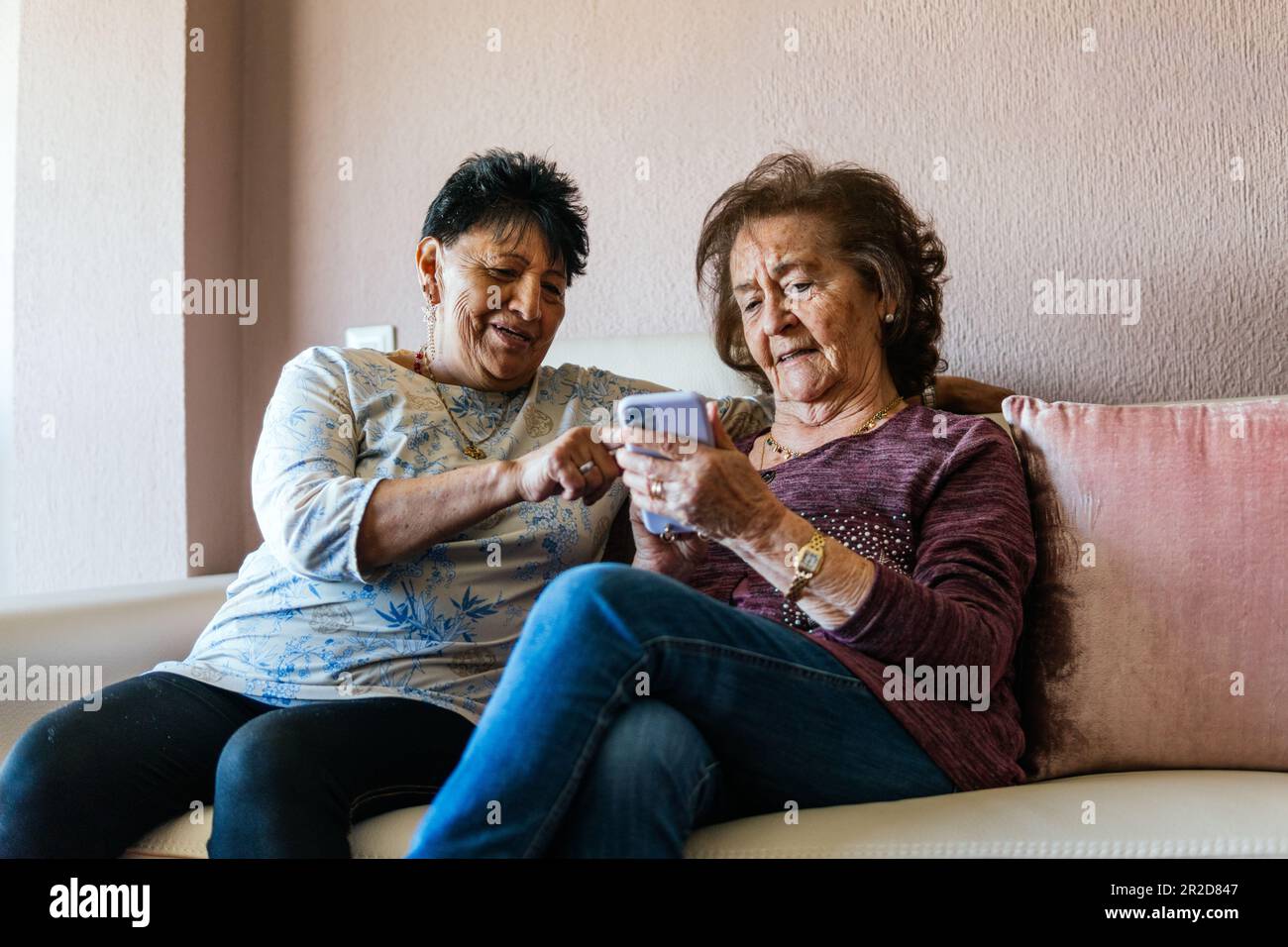 deux vieilles femmes regardant le smartphone assis sur le canapé Banque D'Images