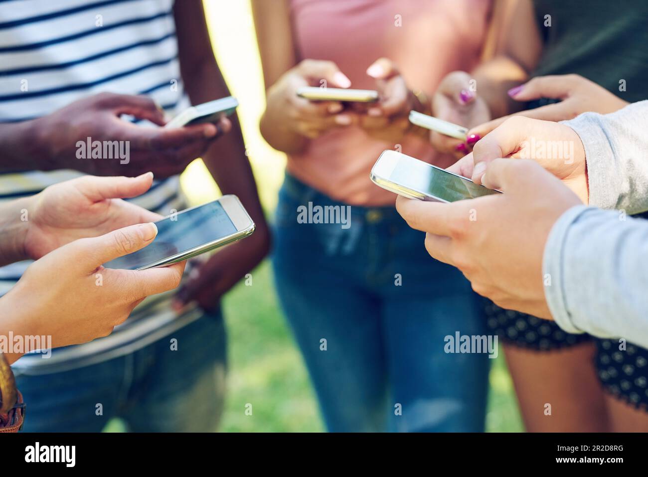 Mains, téléphone et cercle avec SMS, amis et étudiants sur l'application de médias sociaux, le Web ou Internet dans le parc. Hommes, femmes et smartphone en groupe avec le cloud Banque D'Images