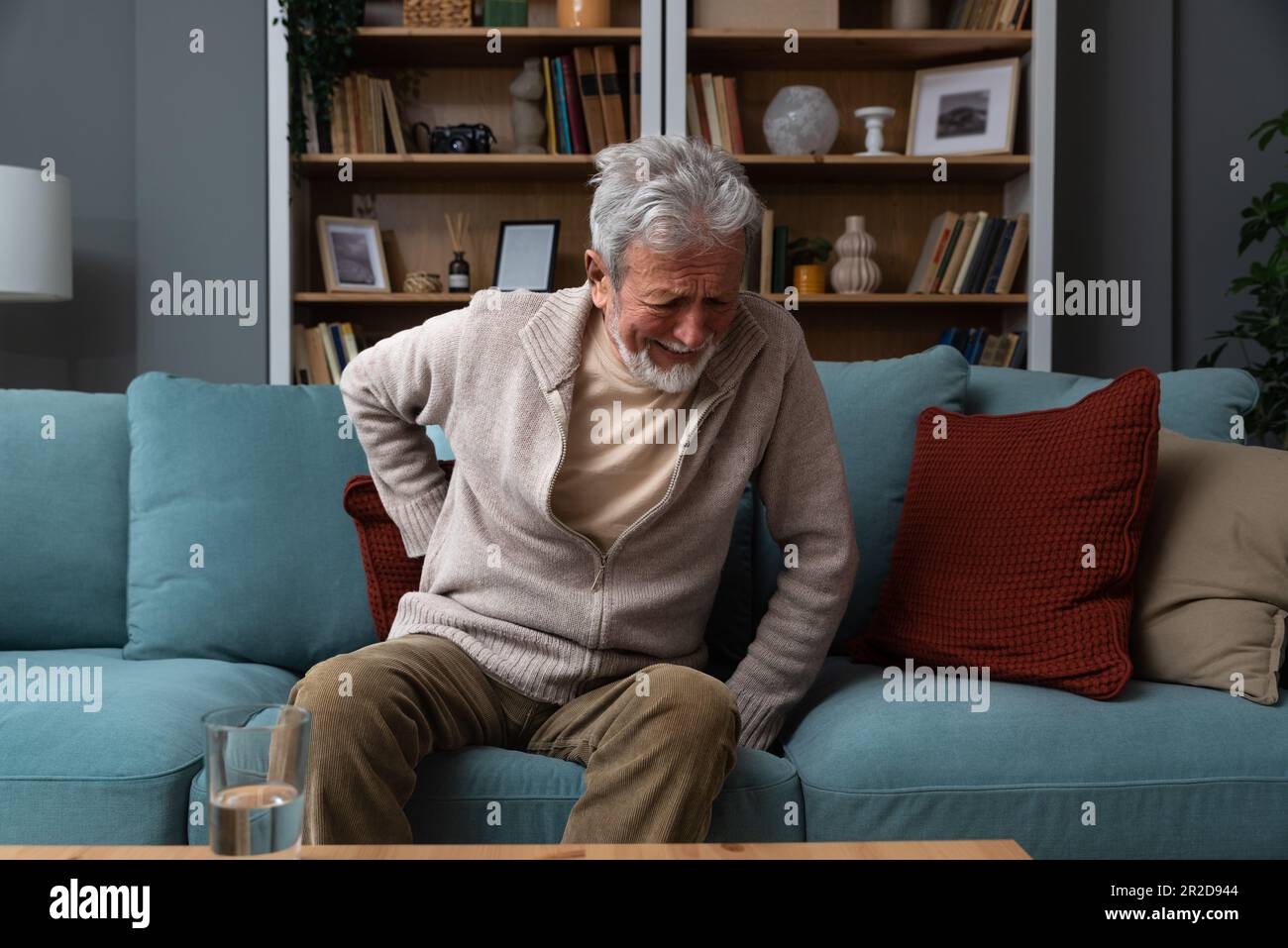 L'homme âgé à cheveux gris âgé à visage rouge âgé se wirthes dans la douleur souffre de la faible tension du dos, le frottement au toucher ou le massage de la longe réduit le mal de dos. Disque dégénératif Banque D'Images