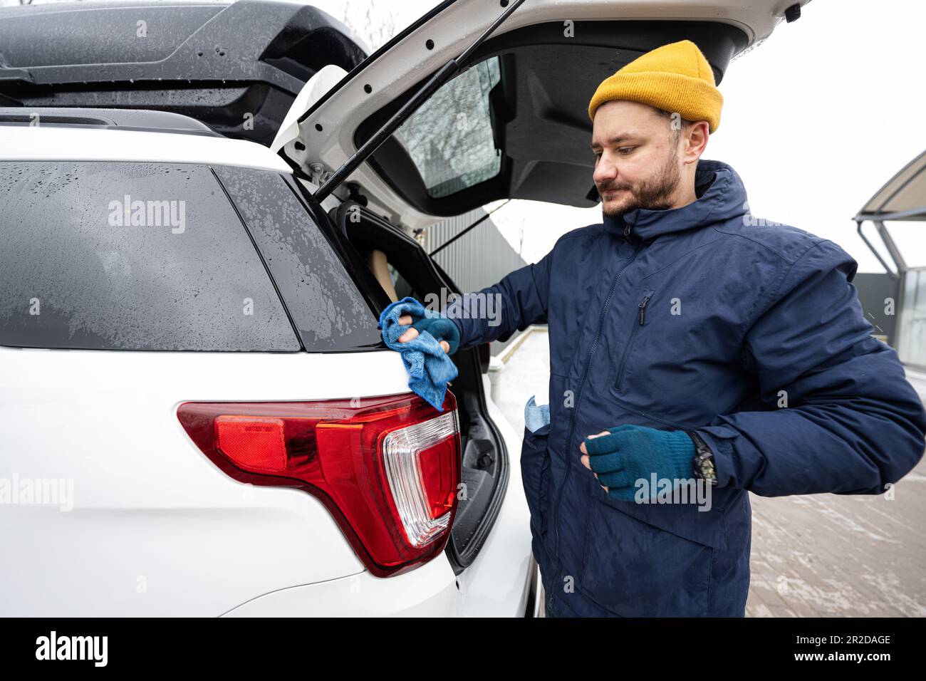 l'homme essuie la voiture suv américaine avec un chiffon en microfibre  après le lavage par temps froid. 21140545 Photo de stock chez Vecteezy