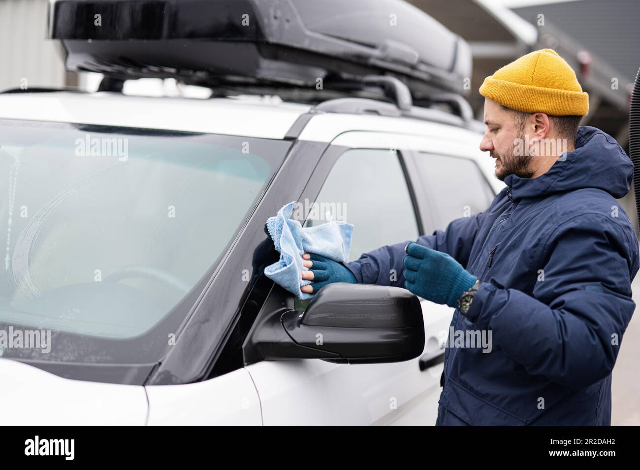 l'homme essuie la voiture suv américaine avec un chiffon en microfibre  après le lavage par temps froid. 21140545 Photo de stock chez Vecteezy