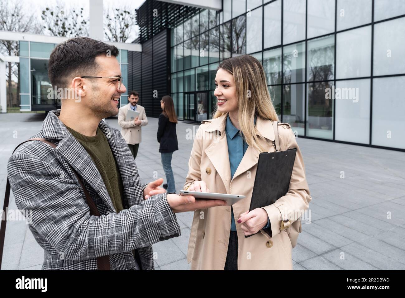 Les jeunes hommes d'affaires se tenant devant le bâtiment du bureau discutant de l'expérience de partage des idées et des suggestions d'affaires de réussite améliorant la collaboration Banque D'Images