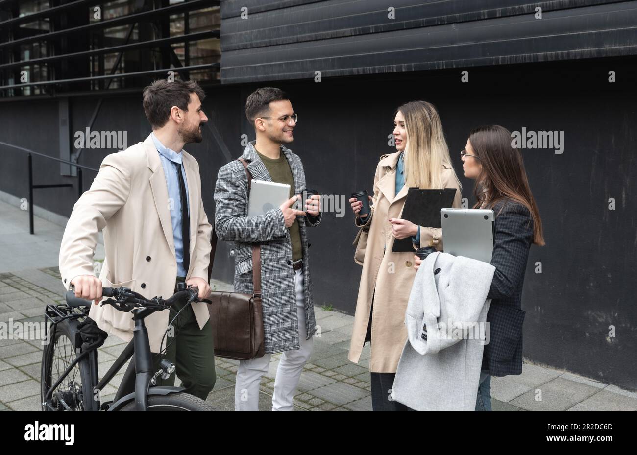 Les jeunes hommes d'affaires se tenant devant le bâtiment du bureau discutant de l'expérience de partage des idées et des suggestions d'affaires de réussite améliorant la collaboration Banque D'Images