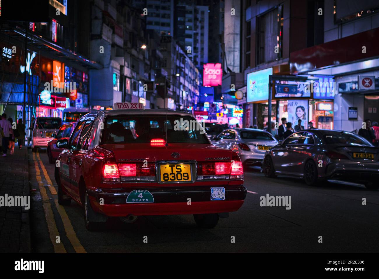Hong Kong, Chine - 10 avril 2023: Taxi rouge dans une rue du centre-ville de Mong Kok et néons lumières de la ville Banque D'Images