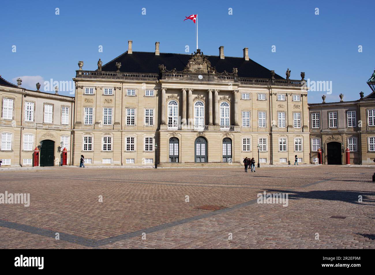 Copenhague, Danemark - 6 avril 2023: Palais Amalienborg de la famille royale du Danemark dans le centre de Copenhague avec quelques touristes et bleu clair s Banque D'Images