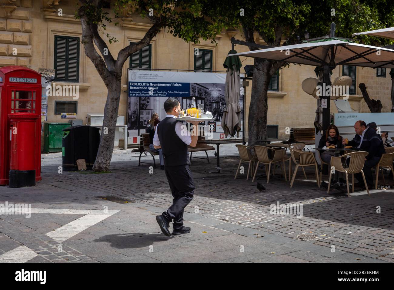 Valletta, Malte - 16 avril 2023: Un serveur transportant un plateau de service au café extérieur de la place de la République. Banque D'Images