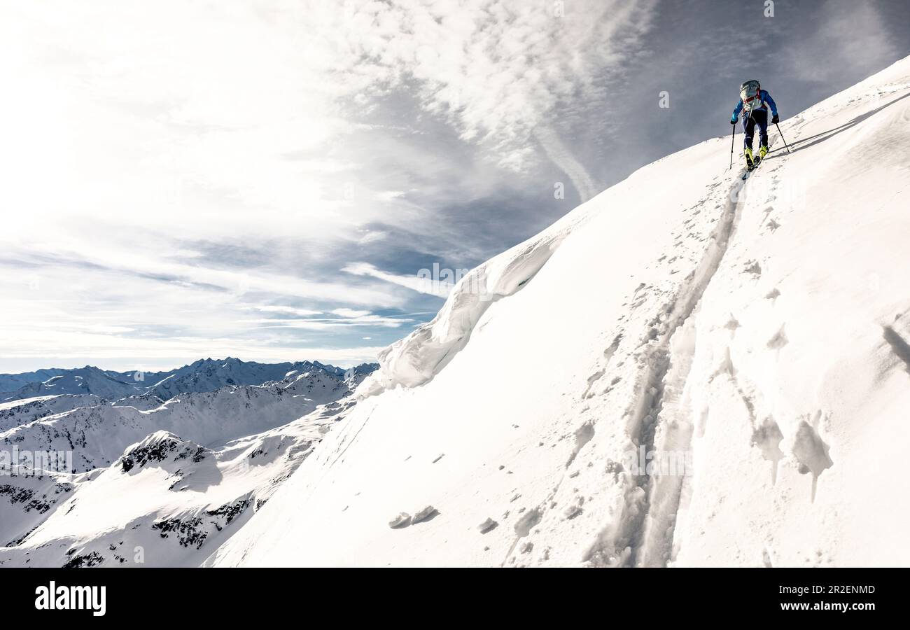 Ski tourer tire un sentier de montée escarpé après un changement vers le sommet de la crête, vallée de l'Alpbach, Tyrol, Autriche Banque D'Images