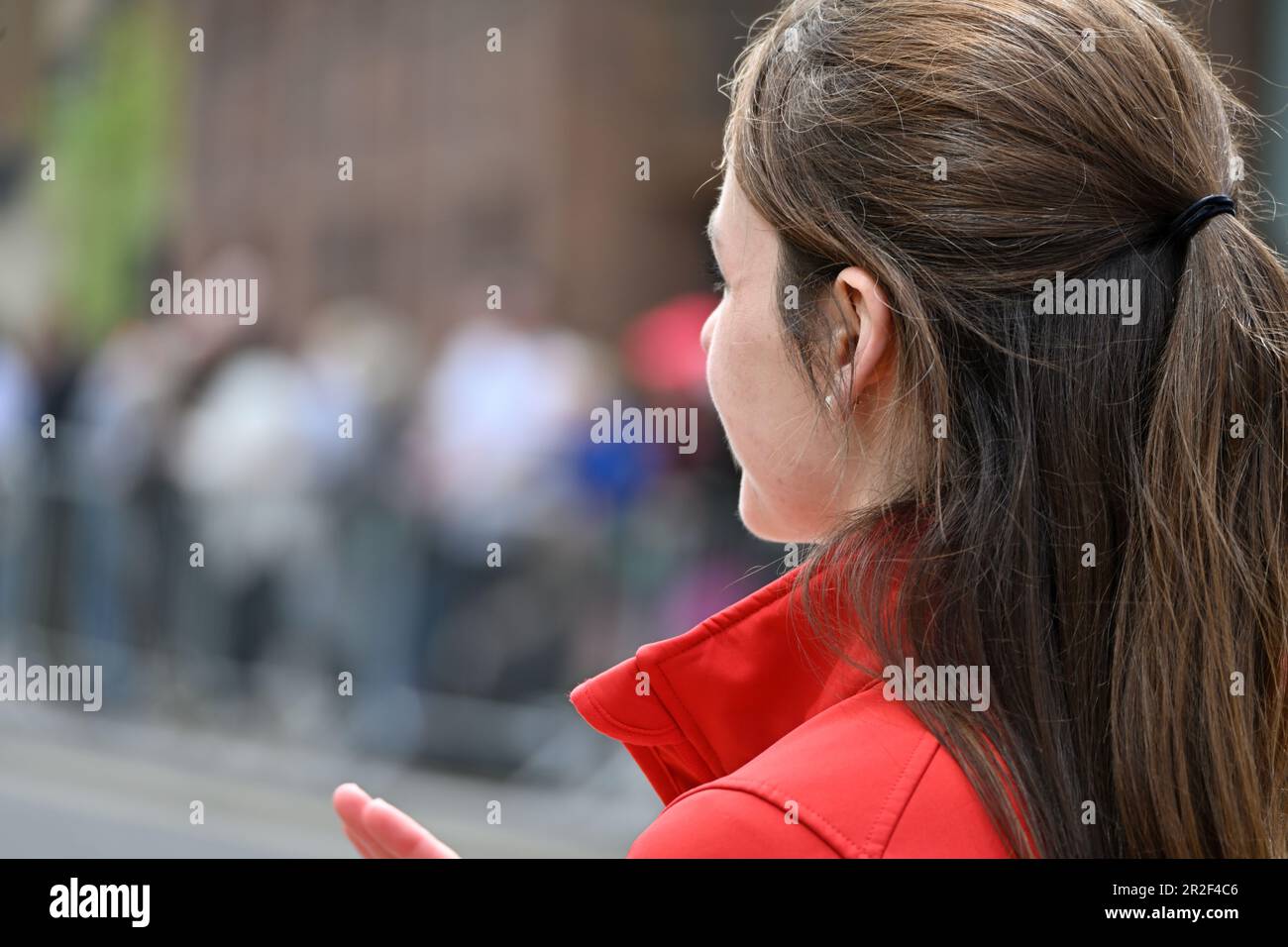 Vue latérale jeune femme avec cheveux bruns certains dans queue poney regardant loin Banque D'Images