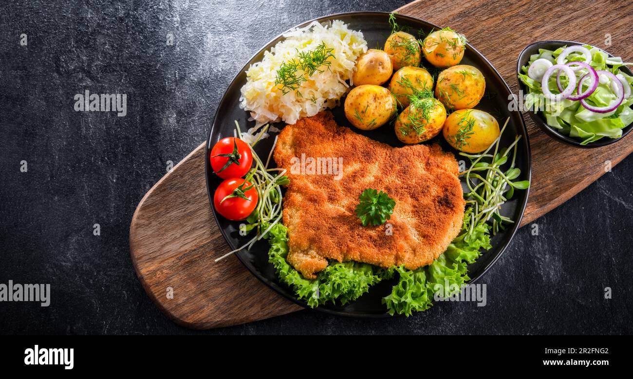 Côtelettes panées de porc enrobées de chapelure servie avec des pommes de terre et du chou Banque D'Images