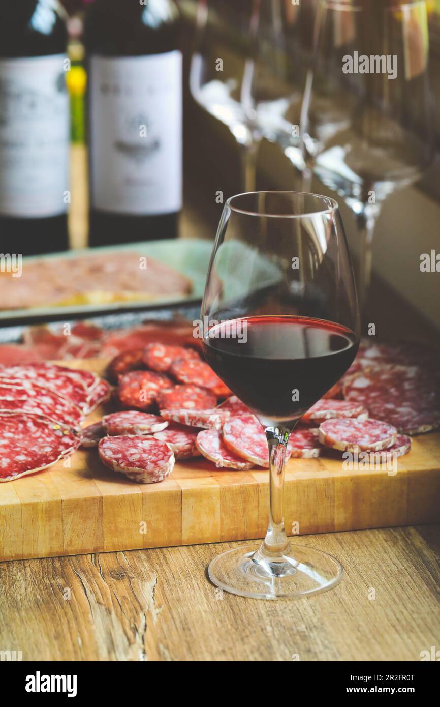 Verre de vin rouge avec différents types de saucisses sur la table Banque D'Images