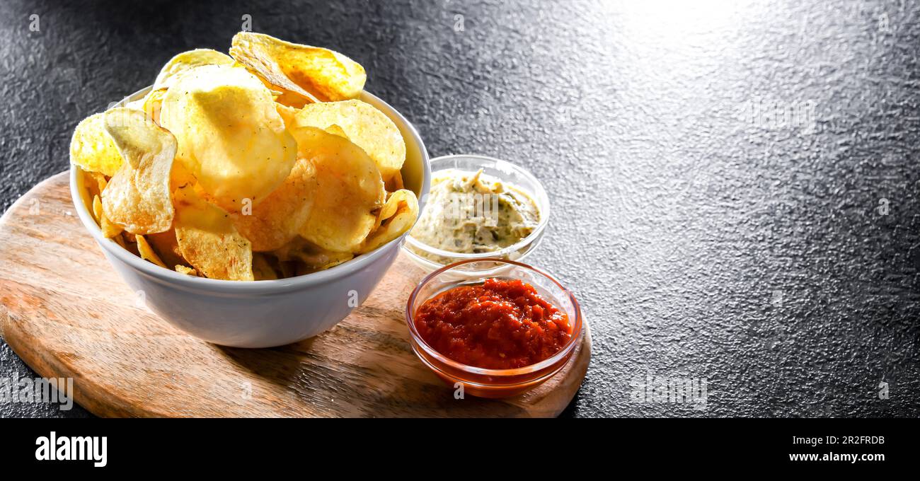 Composition avec un bol de chips de pomme de terre et de sauces à trempette Banque D'Images