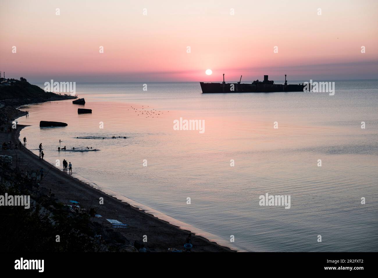 L'épave Evangelia, les gens et les mouettes au lever du soleil sur la côte de la mer Noire à Costinesti, Constanta, Roumanie. Banque D'Images