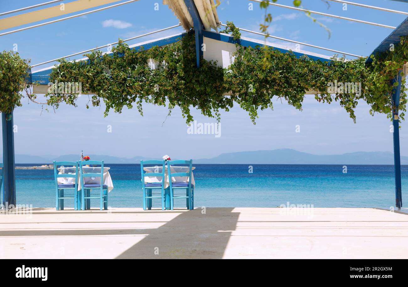 Kokkari, deux tables de restaurant isolées entre les tavernes du port donnant sur la mer sur l'île de Samos en Grèce Banque D'Images