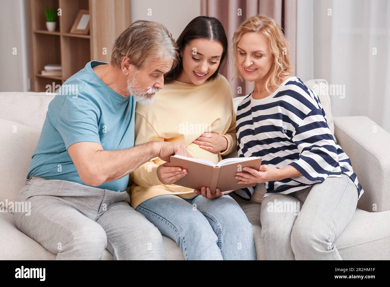 Une femme enceinte heureuse qui passe du temps avec ses parents à la maison. Réaction des grands-parents à l'avenir de leur petit-fils Banque D'Images