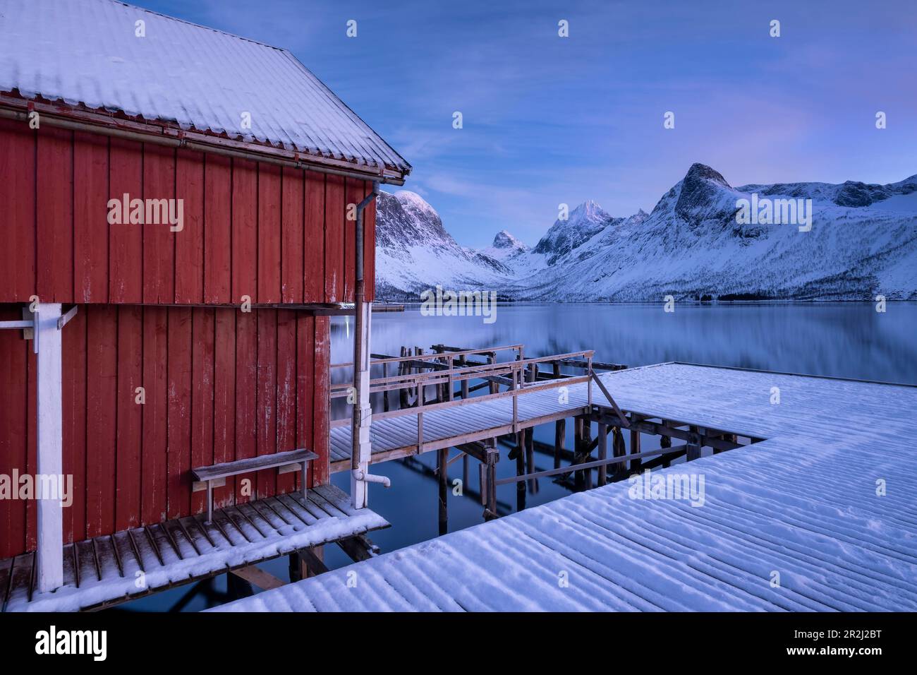 Rorbuer Fishing Hut et jetée en bois surplombant Bergsfjord et la chaîne de montagnes de Bergsbotin, Bergsbotin, Senja, comté de Troms og Finnmark, Norvège Banque D'Images