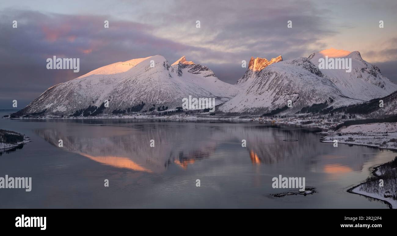 Lumière de l'aube au-dessus du village de Bergsbotn et de Bergsfjord soutenu par la chaîne de montagnes de Bergsbotn en hiver, Senja, comté de Troms og Finnmark, Norvège Banque D'Images