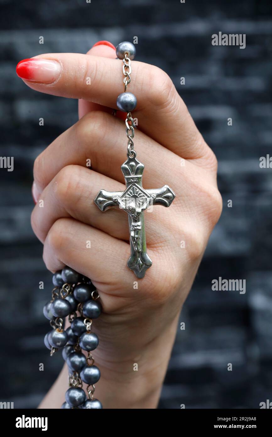 Femme priant avec un crucifix argenté et un rosaire avec des perles, concept de religion chrétienne, de foi et de prière, Vietnam, Indochine, Asie du Sud-est Banque D'Images