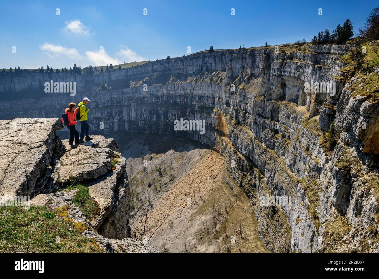 Deux personnes s'élèvent sur une falaise et regardent le Creux du Van rondel, le Jura suisse, Neuchâtel, Suisse Banque D'Images