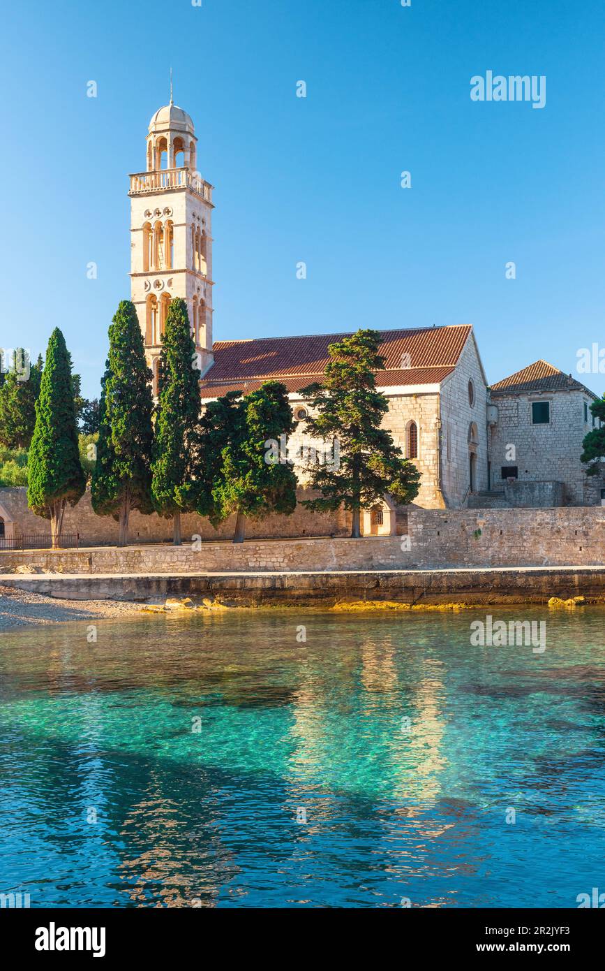 Baie Adriatique sur l'île de Hvar avec monastère franciscien dans la région de Dalmatie, Croatie au lever du soleil. Orientation verticale. Destination de vacances d'été Banque D'Images