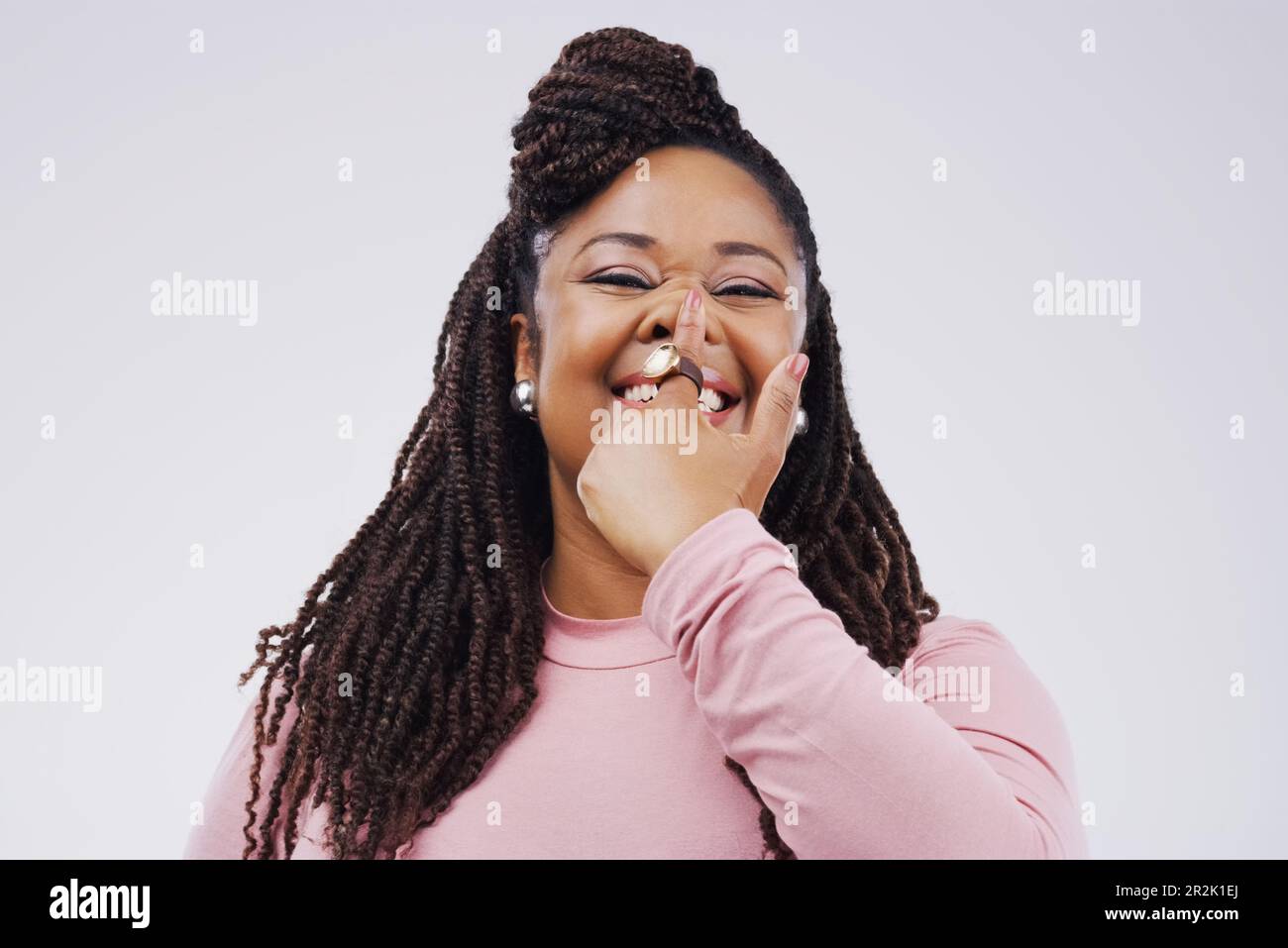 Portrait, visage drôle et doigt sur le nez avec une femme noire en studio sur un fond gris regardant ridicule ou goofy. Comédie, comique et narine avec un Banque D'Images