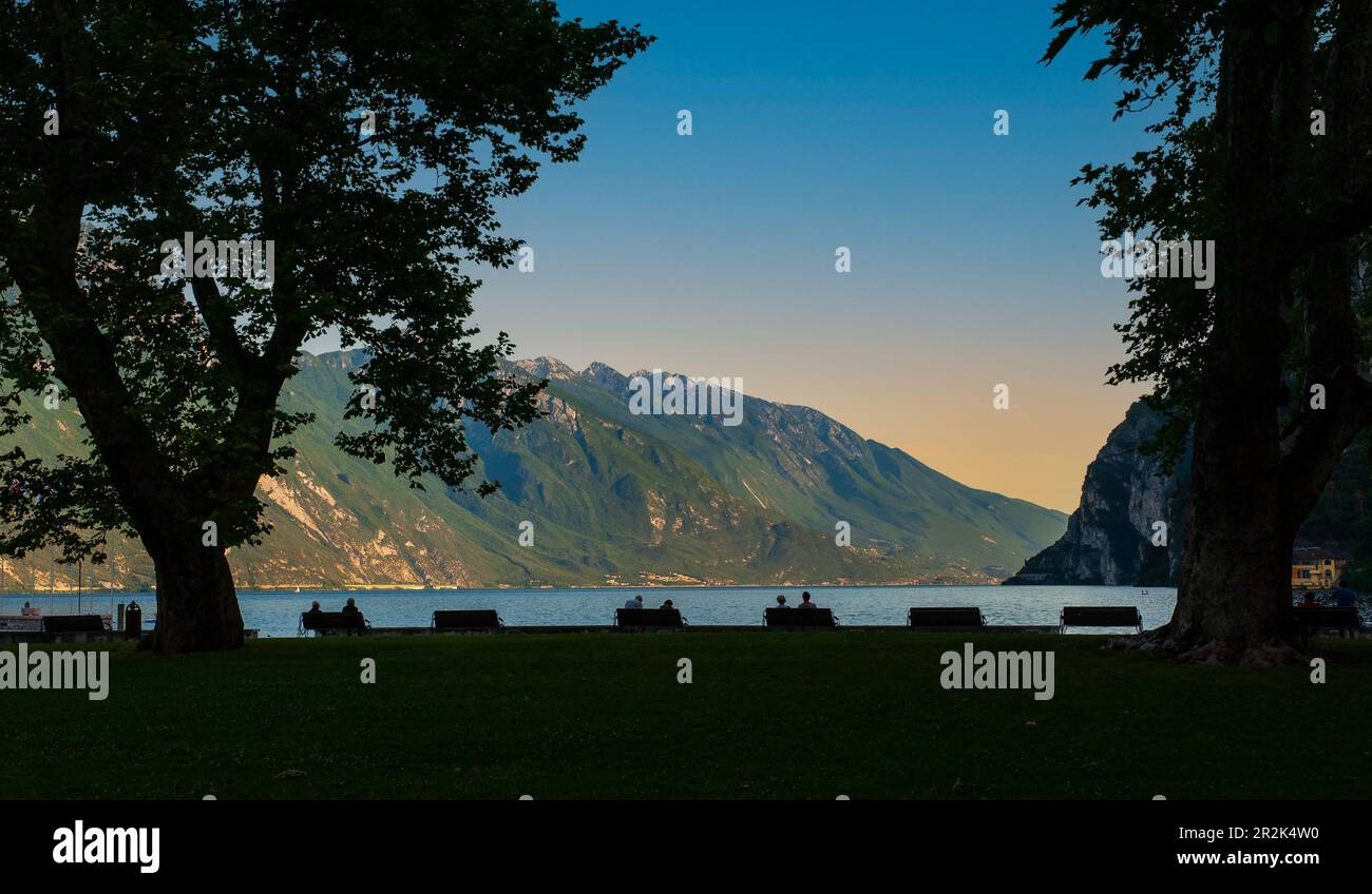 Personnes attendant le coucher du soleil sur la rive du lac de Garde, à Riva del Garda. Trento. Italie Banque D'Images