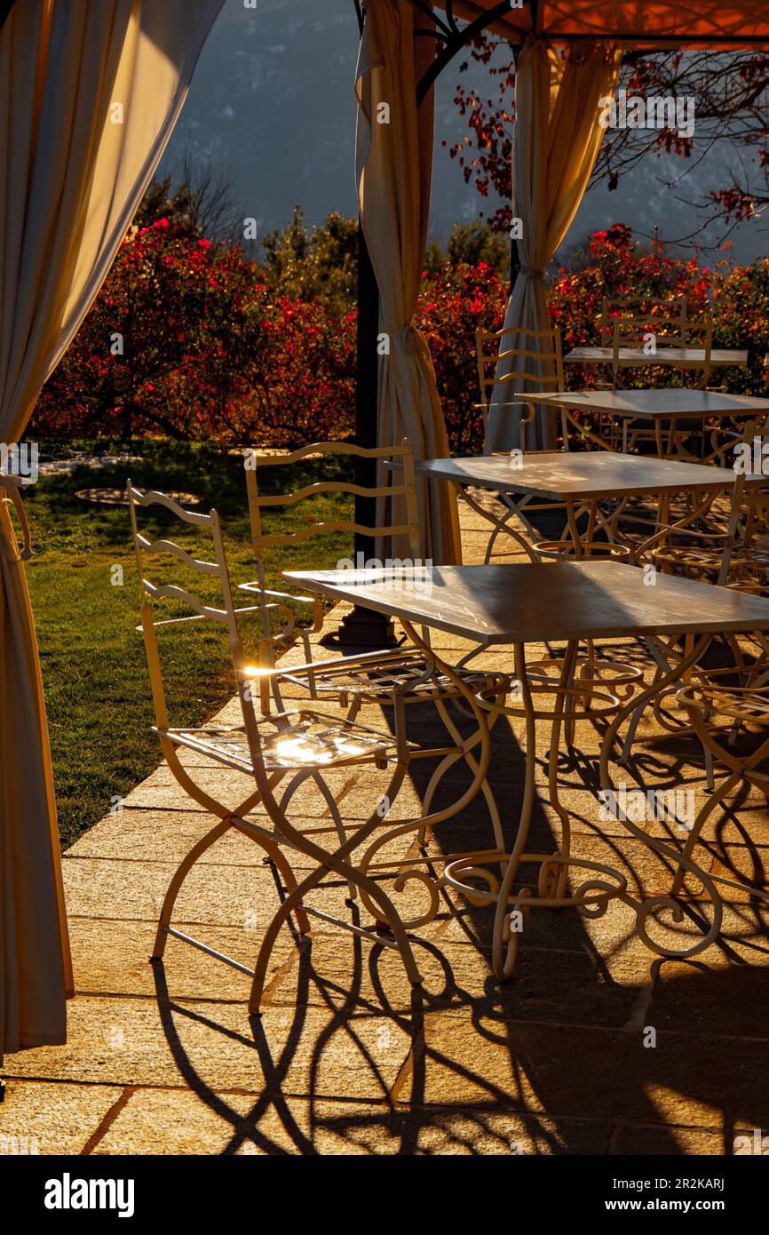 Restaurant vide avec chaises et table plein air avec lumière du soleil en automne à Lugano, Tessin en Suisse. Banque D'Images Restaurant vide avec chaises et table plein air avec lumière du soleil en automne à Lugano, Tessin en Suisse. Banque D'Images