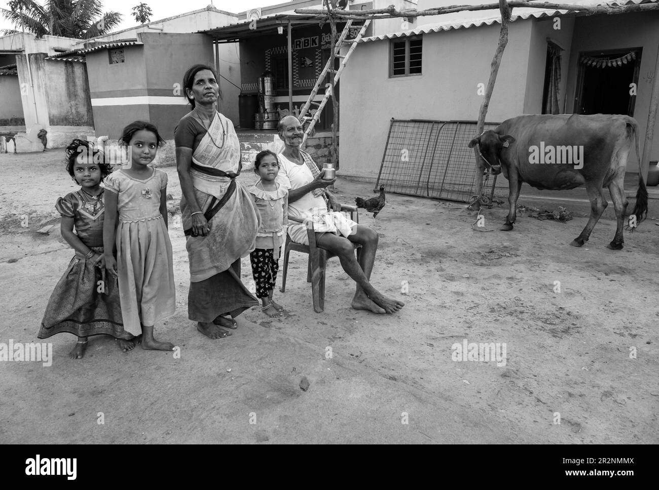 Famille rurale indienne posant devant leur modeste maison Banque D'Images