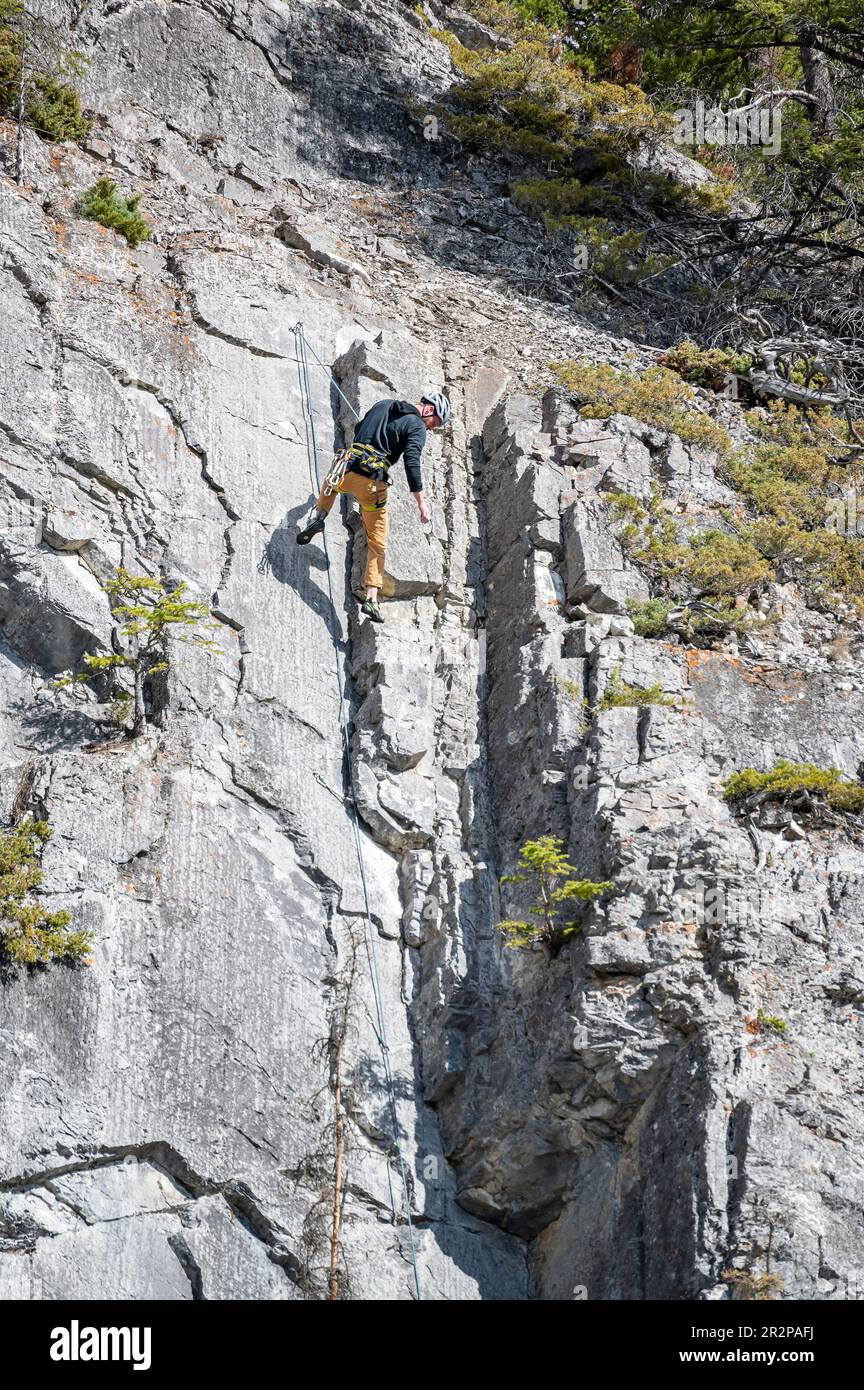 Parc national Banff, Alberta, Canada – 06 mai 2023 : un homme en ascension de rocher regarde vers le bas depuis le sommet Banque D'Images