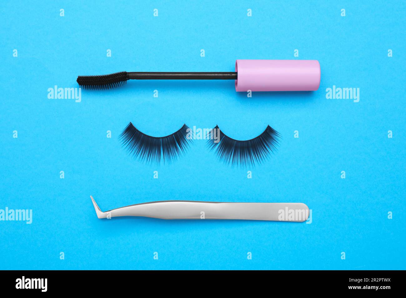 Composition de la couche plate avec faux cils, pinceau mascara et brucelles  sur fond bleu clair Photo Stock - Alamy